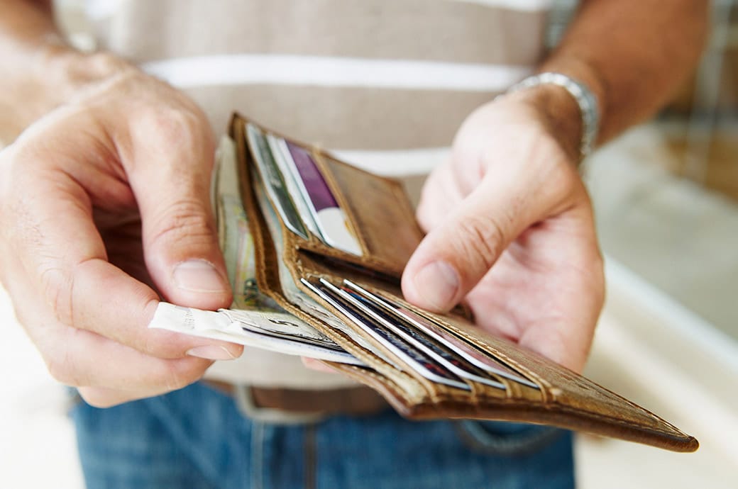 A close up of a man holding a wallet and pulling money out